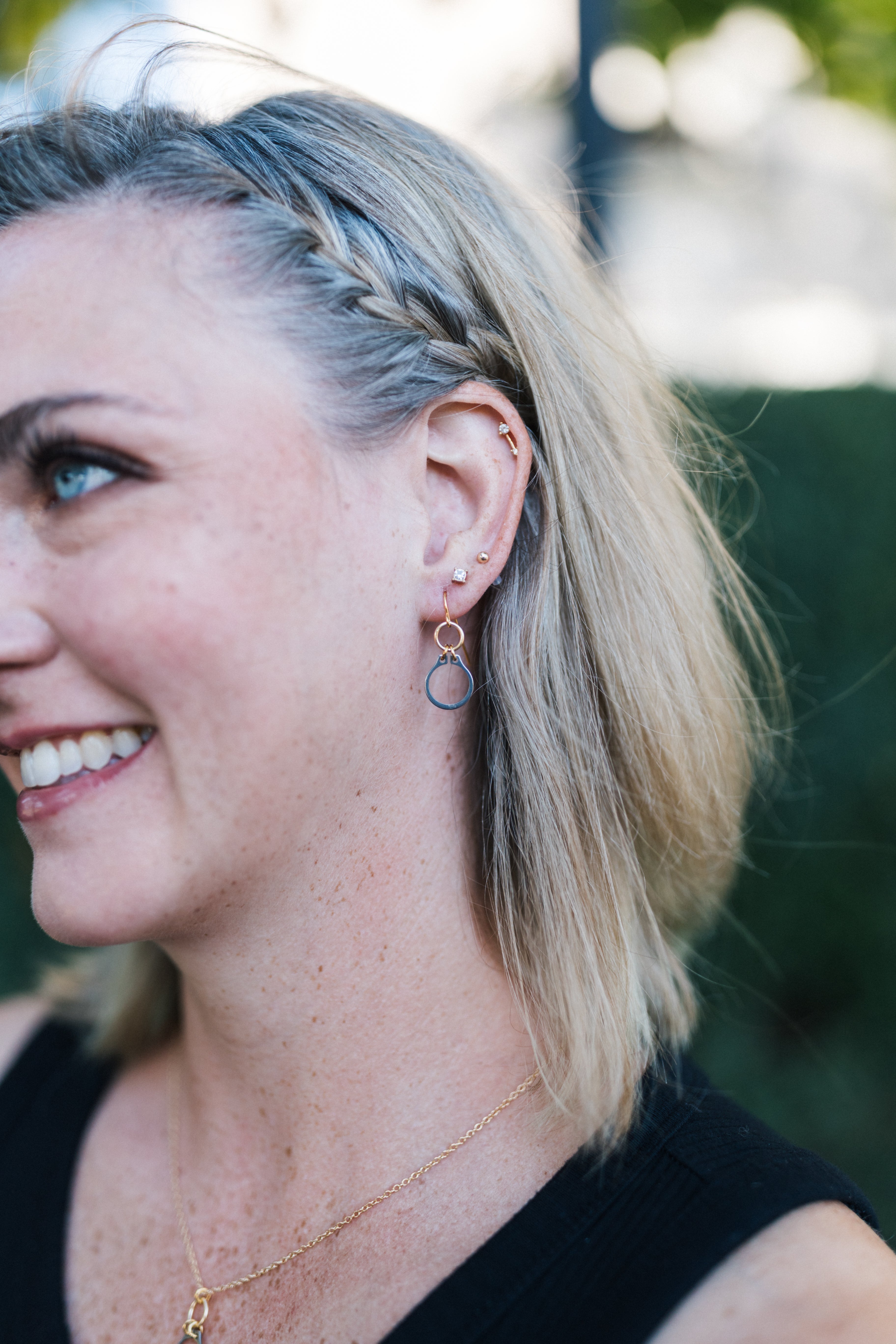 Woman with braided hair wearing silver and gold dangle earrings for sale by Mend on the Move