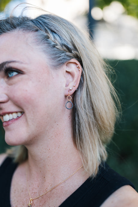 Woman with braided hair wearing silver and gold dangle earrings for sale by Mend on the Move