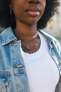 Person wearing a denim jacket and white shirt with a copper necklace for sale by Mend on the Move