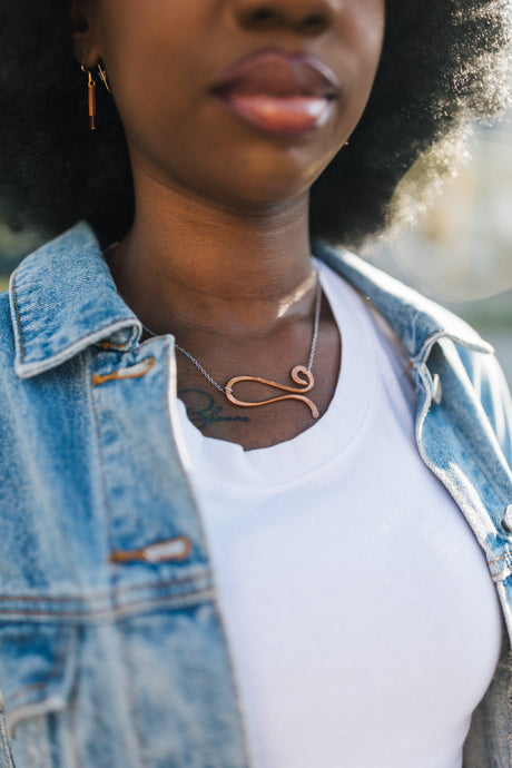 Person wearing a denim jacket and white shirt with a copper necklace for sale by Mend on the Move