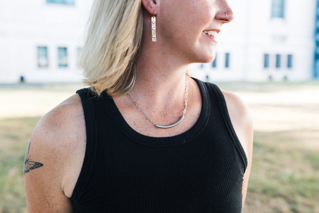 Person wearing a black tank top with silver necklace for sale by Mend on the Move
