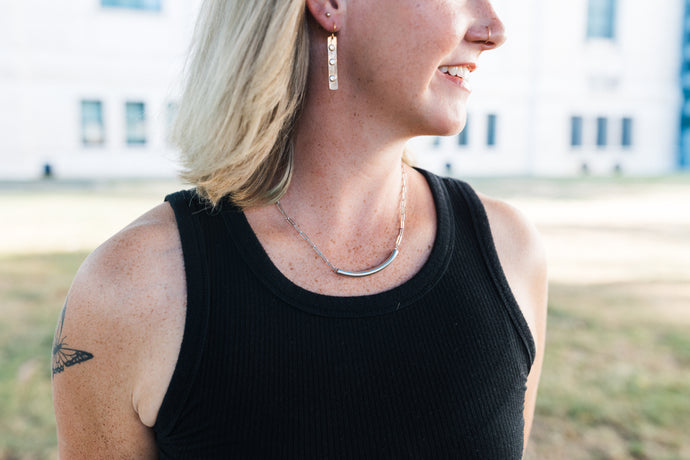 Person wearing a black tank top with silver necklace for sale by Mend on the Move