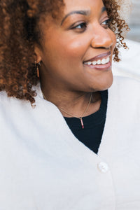 Woman wearing a white sweater with a blurred background, wearing a copper necklace with gold plated chain for sale by Mend on the Move