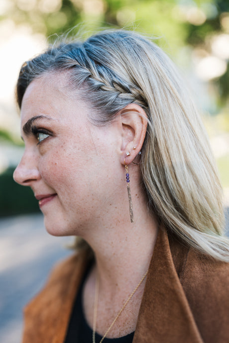 Woman with braided hair wearing copper earrings with purple amethyst beads for sale by Mend on the Move 