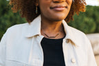 Woman wearing a light-colored jacket over a black top with a copper patina necklace for sale by Mend on the Move 
