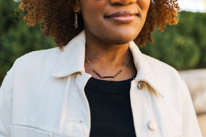 Woman wearing a light-colored jacket over a black top with a copper patina necklace for sale by Mend on the Move 
