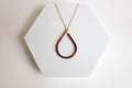 Teardrop-shaped copper pendant necklace for sale by Mend on the Move on a white hexagonal stand