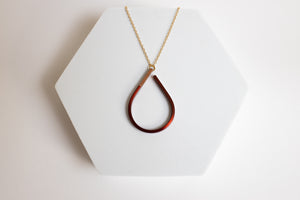 Teardrop-shaped copper pendant necklace for sale by Mend on the Move on a white hexagonal stand