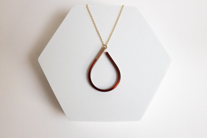 Teardrop-shaped copper pendant necklace for sale by Mend on the Move on a white hexagonal stand
