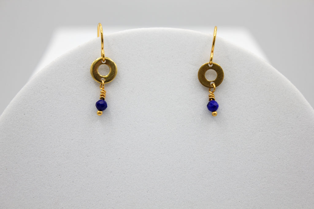 Gold earrings with lapis blue beads on a white stand