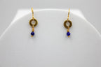 Gold earrings with lapis blue beads on a white stand