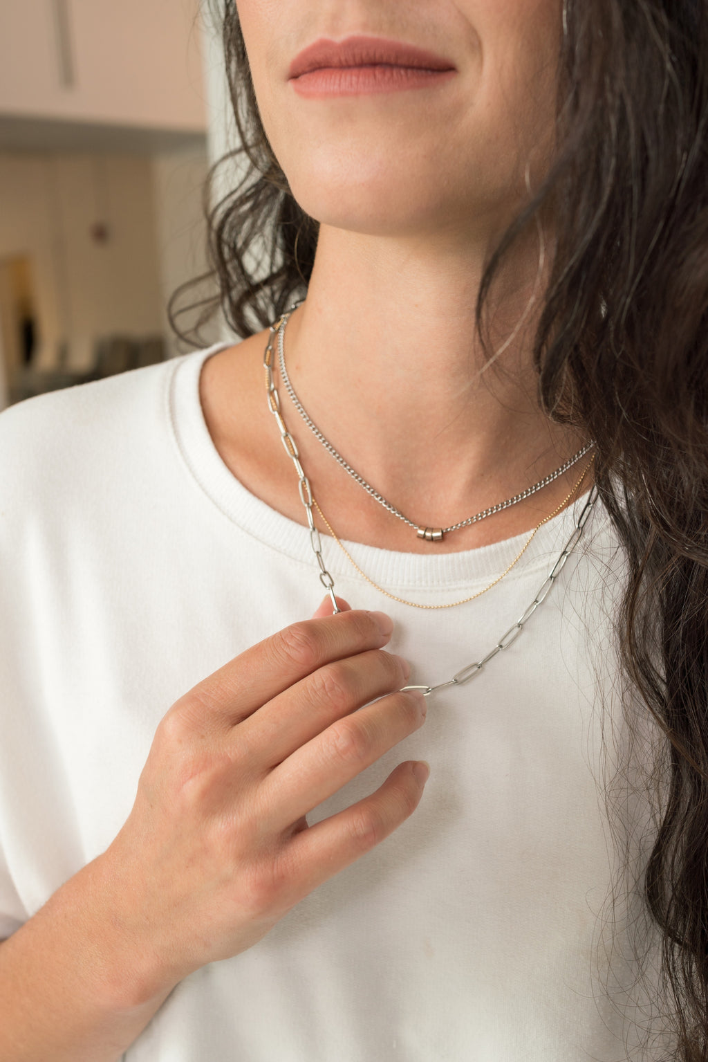 woman touching three strand necklace